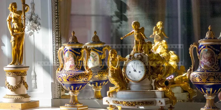 clock in front of a mirror surrounded by two vases