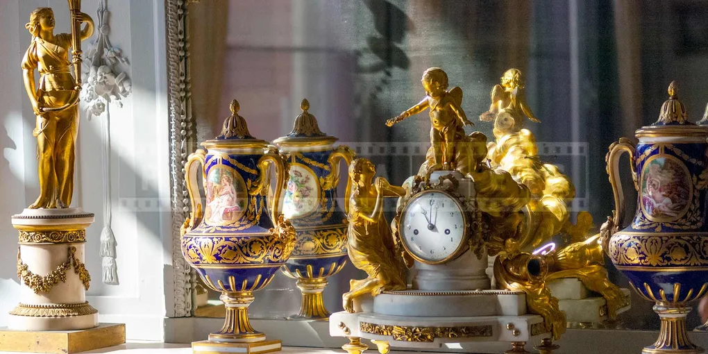 clock in front of a mirror surrounded by two vases