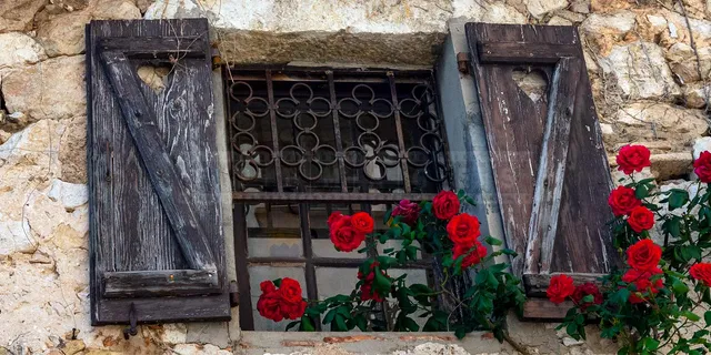 Beautiful medieval window with red roses in Eze Village