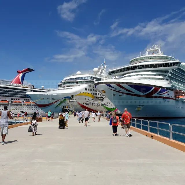 Three large cruise ships docked side by side at a sunny port in Mexico.