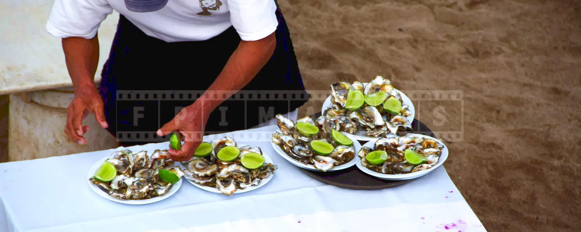 Mexican cook garnishing plates with dozen oysters with fresh lime slices