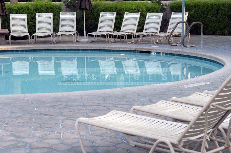 The Clear Blue Pool Reflecting the White Lounge Chairs