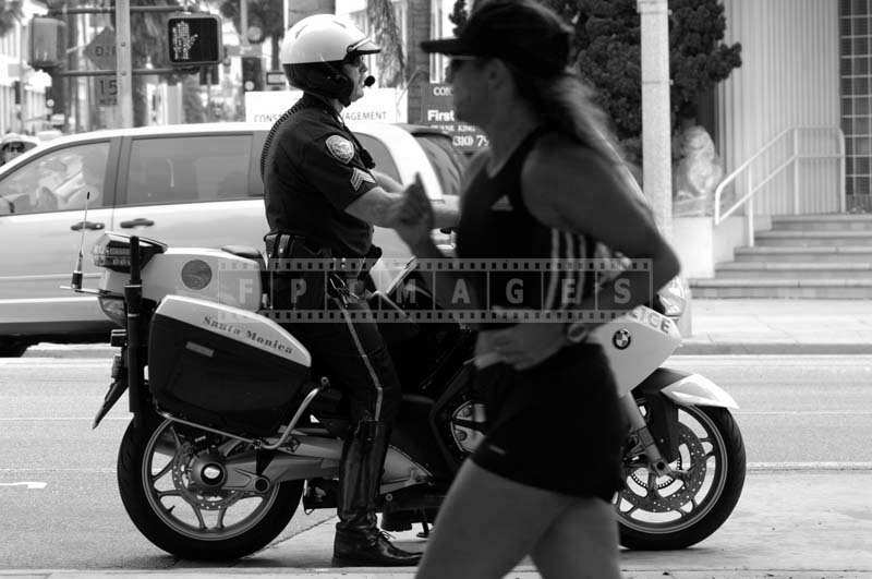 A Policeman Patrolling on a Bike as a Jogger Strolls on