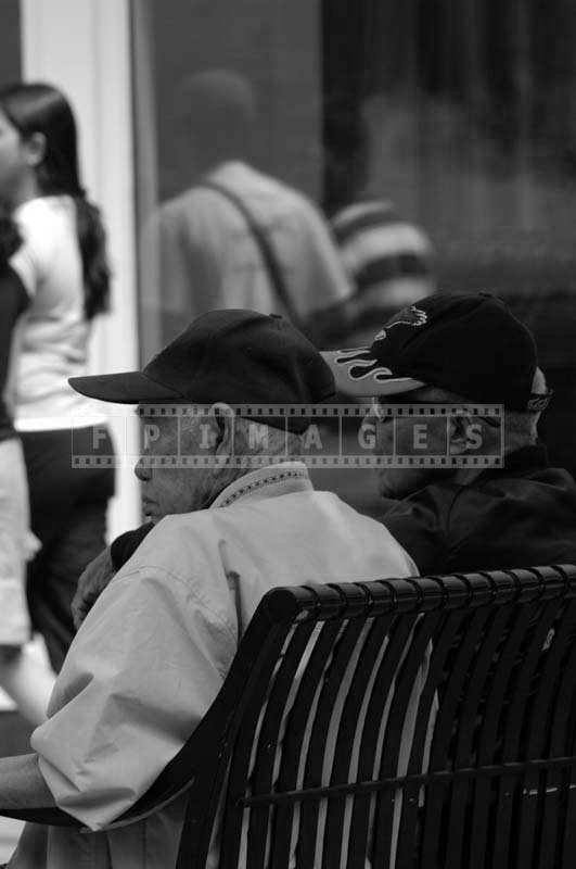 Two Men Wearing a Sports Cap Sitting on a Bench