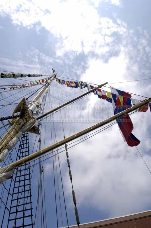 Looking up at the tall mast decorated with flags