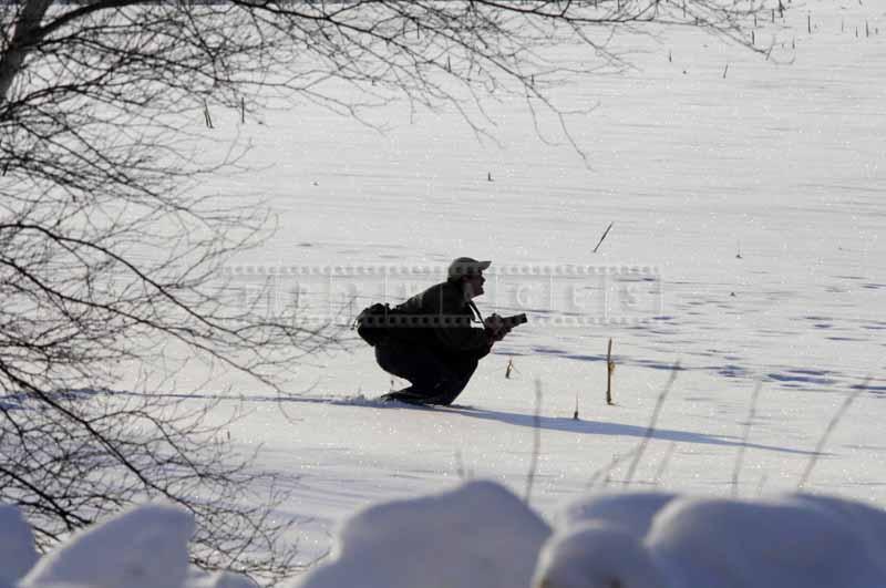 Photographer crouching in snow