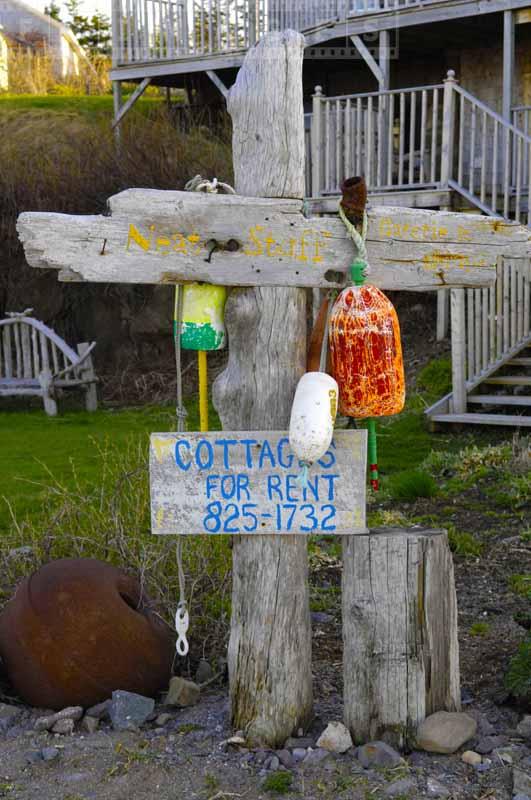 A sign made from driftwood and colorful buoys