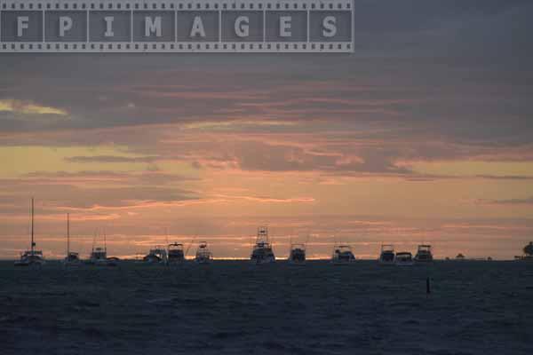 Pink clouds and anchored boats, sunrise