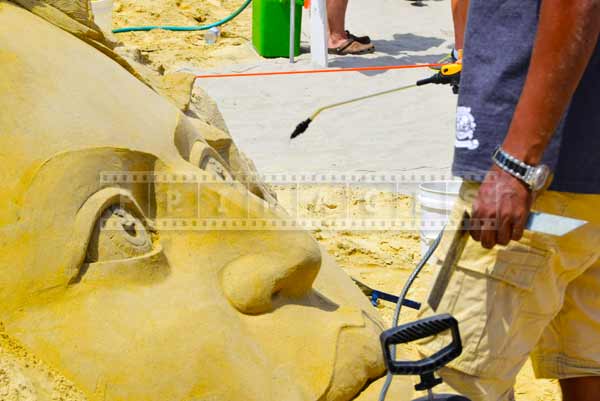 Spraying mist of water on sand sculpture