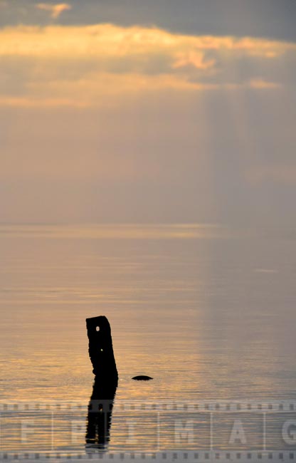 Golden sun rays shine through the clouds, coastal landscape