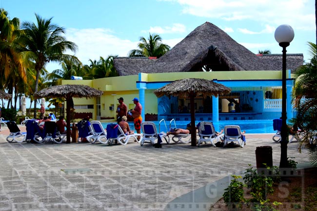 People enjoying sun and drinks near the pool