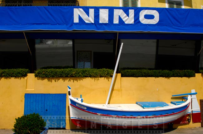 Colorful scenic fishing village cityscape - yellow house and white and blue boat