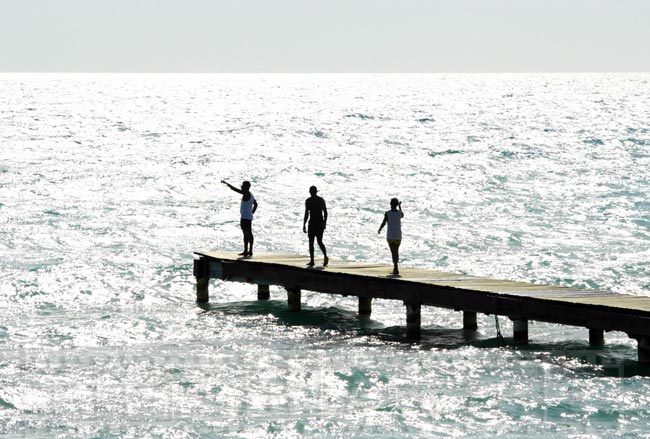 Three people at the wooden pier near the beach