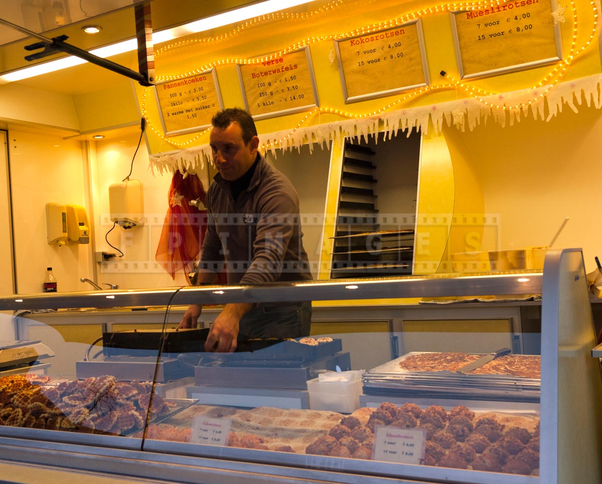 A man selling Belgian waffles and othe baked goods