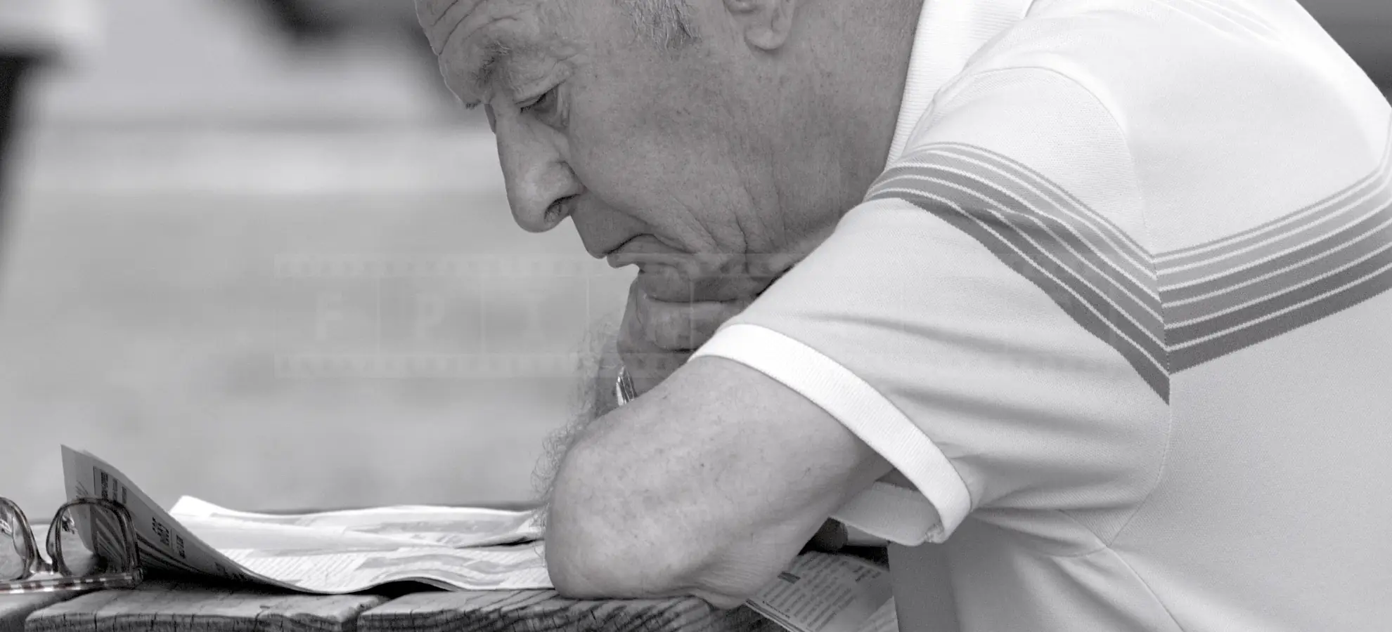Black and white portrait of an old man reading newspaper