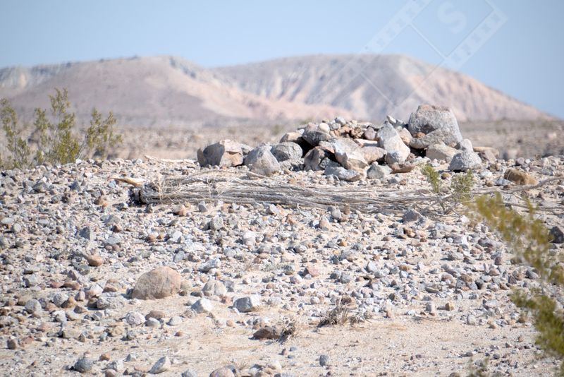 A barren, rocky landscape stands undisturbed under the clear sky, a testament to the rugged resilience of nature.