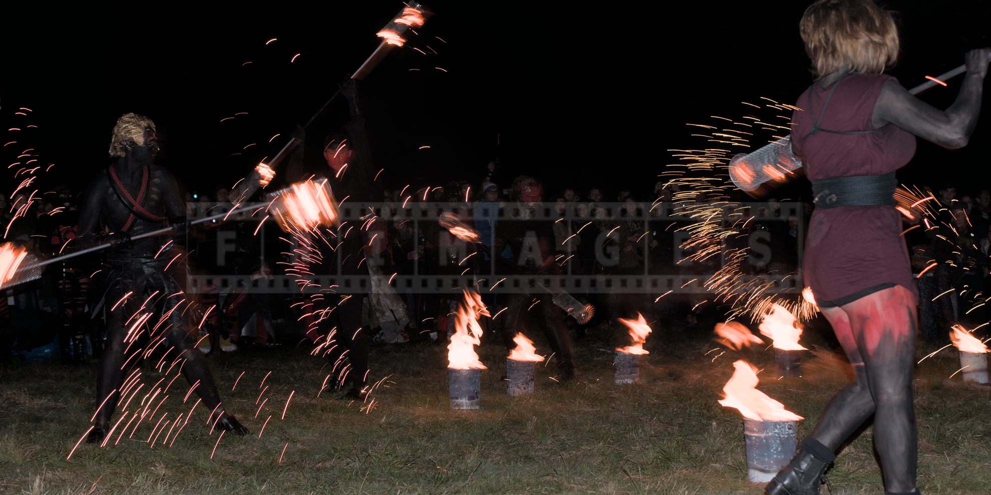 Fire sparkles fly as artist perform in front of the spectators at Beltane Fire Show at night