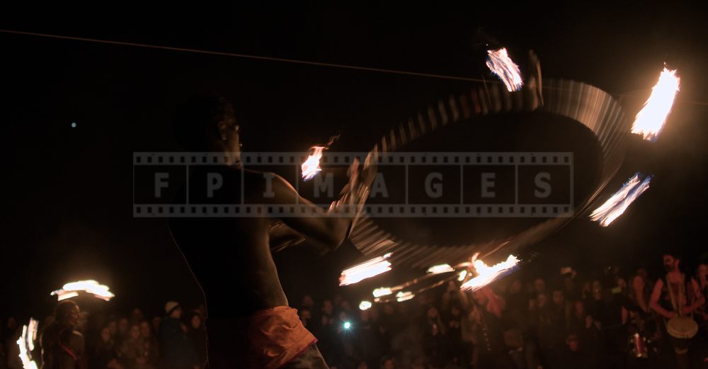 Spinning fire hoop at night to the beat of the drums